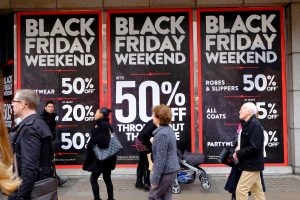 Shoppers walk past a department store with signs reading “Black Friday weekend, 50% off”. Oxford Street, London